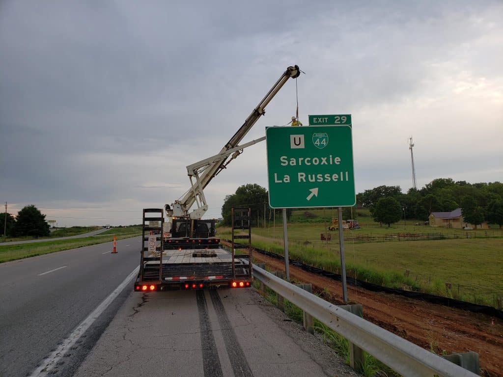 crane and worker placing an exit sign for Sarcoxie, La Russell on highway