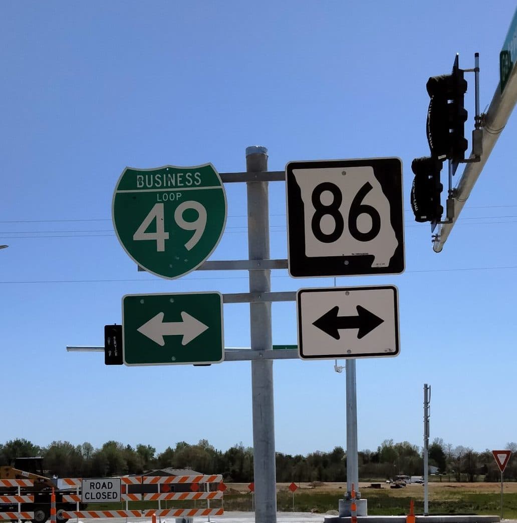 Two street signs, one green with 49, and other black and white with 86