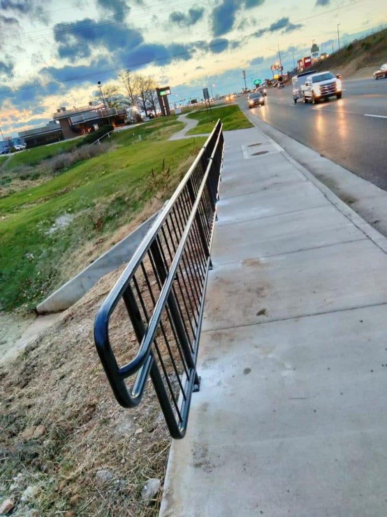 black handrail on a sidewalk next to a busy street